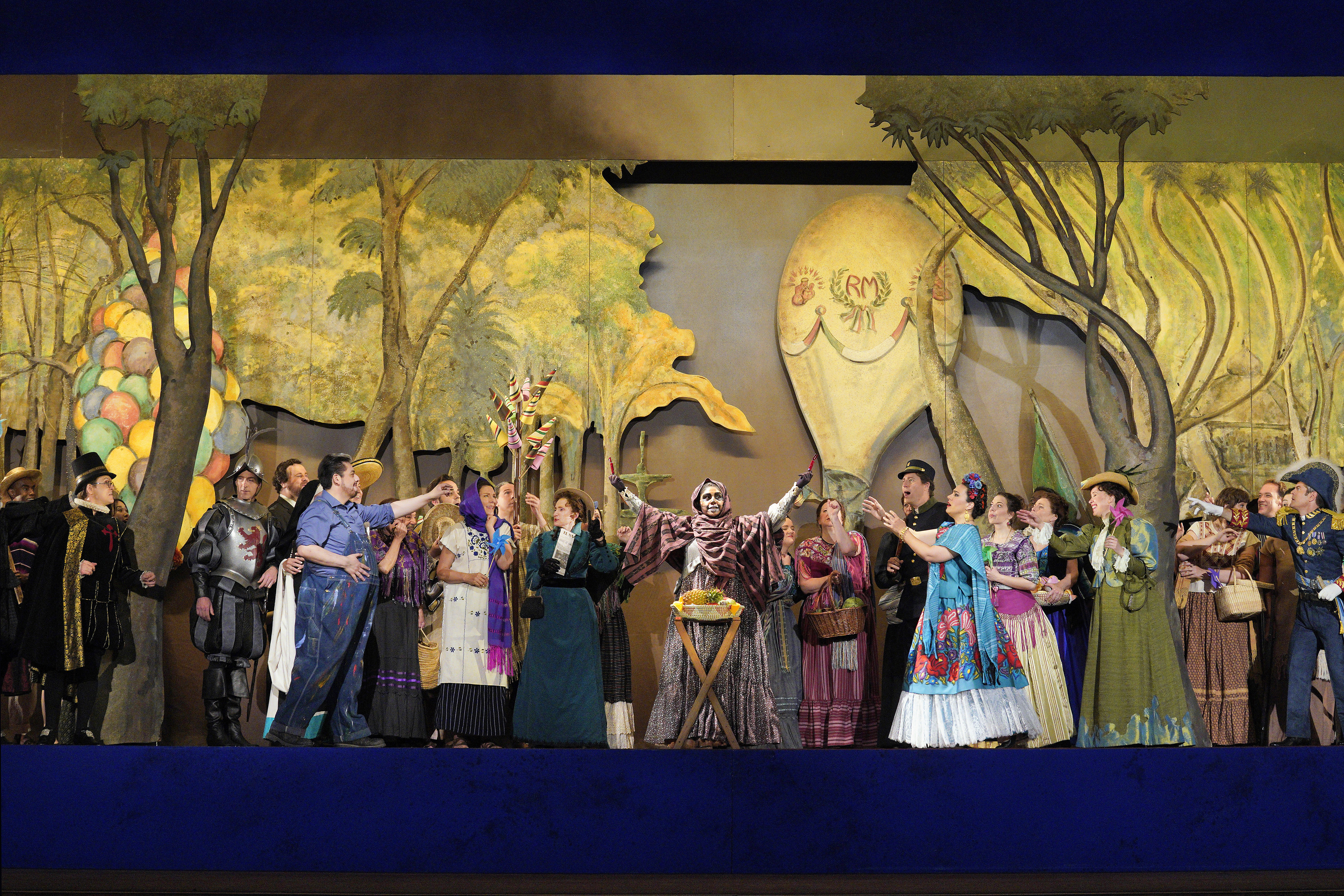 A skeleton figure raises both arms beside a woman in a turquoise floral dress as a large ensemble gathers against a painted forest backdrop.